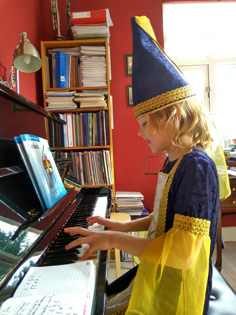 Een verklede leerling met een tovenaarshoed speelt piano